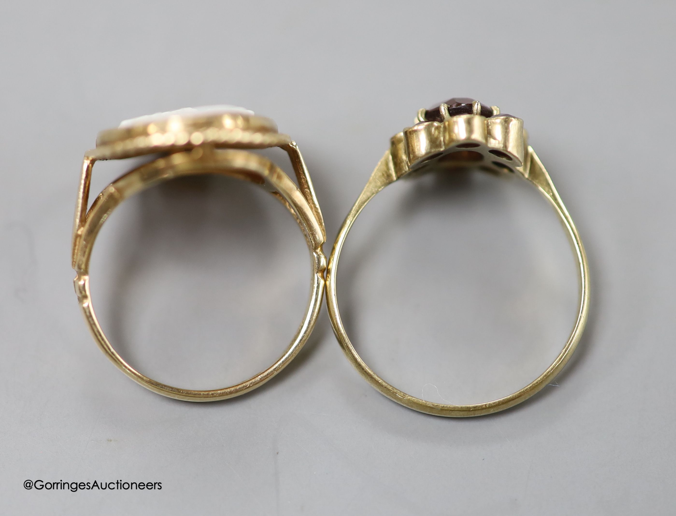 A modern 9ct gold and 'Three Graces' oval cameo shell ring, size K, gross 3.2 grams and a 333 (8kt) yellow metal and garnet cluster ring, size O/P, gross 1.7 grams.
